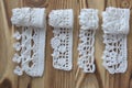 Handmade crocheted cotton organic lace ribbons on wooden background. White original crochet frame, Knitted pattern backdrop with