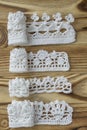 Handmade crocheted cotton organic lacen ribbons on wooden background. White original crochet frame, Knitted pattern backdrop with