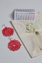 Handmade crocheted earrings. Greeting card. Nearby is a fragment of the calendar with the month of December. On white background