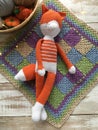 Handmade crocheted Fox toy lies on a multicolored blanket