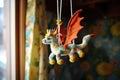 a handmade dragon toy hanging from a baby mobile