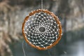 Handmade dream catcher on background of rocks and lake