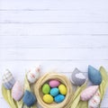 Easter nest with colorful eggs surrounded by fabric tulips flowers on a background of white wooden boards. A beautiful spring Royalty Free Stock Photo