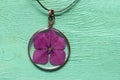 Handmade epoxy resin jewelry. pendant, hydrangea in copper frame. dried flowers. herbarium, oshibana. on green