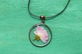 Handmade epoxy resin jewelry. pendant, rose in copper frame. dried flowers. herbarium, oshibana, phytotherapy. on green wooden