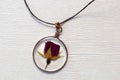 Handmade epoxy resin jewelry. pendant, rose in copper frame. dried flowers. herbarium, oshibana. on white wooden
