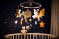 Handmade felt toys above the newborn crib with light garland in the night. Baby crib mobile, first baby eco-friendly toys, cozy