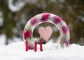 Handmade frozen wreath in shape of ring cake made of ice, pink tulip flowers with pink heart and burning red candles in snow Royalty Free Stock Photo