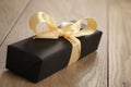 Handmade gift black paper box with yellow ribbon bow on wood table Royalty Free Stock Photo