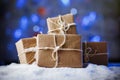 Handmade gift boxes from craft paper over snowy wooden table in blue light. Royalty Free Stock Photo