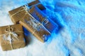 Handmade gift boxes from craft paper over snowy wooden table in blue light. Royalty Free Stock Photo