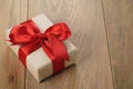 Handmade gift brown paper box with red ribbon bow on wood table Royalty Free Stock Photo