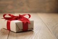 Handmade gift brown paper box with red ribbon bow on wood table Royalty Free Stock Photo