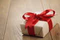 Handmade gift brown paper box with red ribbon bow on wood table Royalty Free Stock Photo