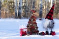 Handmade gnome with decorated Christmas tree in the winter forest Royalty Free Stock Photo