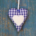 Handmade heart shape against blue wooden surface.