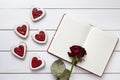 Handmade heart shaped cookies with empty notebook and rose flower on white wooden background for Valentines day. Royalty Free Stock Photo