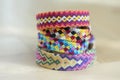 Handmade homemade colorful natural woven bracelets of friendship isolated on light blue background, pile of colorful handcrafts