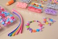 Handmade jewelry kit for kids. Colorful beads, wristbands and bracelets on beige background, closeup