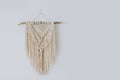 Handmade macrame decoration hanging on a white empty wall.
