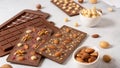 Handmade milk chocolate bars with nuts and dried fruits with molds and ingredients on white background. Side view, close up Royalty Free Stock Photo