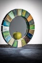 Handmade mirror in a wooden toned frame texture cracked paint with reflection green apple on the table Royalty Free Stock Photo