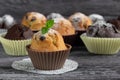 Handmade muffins with a leaf of mint on a wooden table