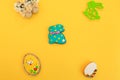 Handmade multi-colored gingerbread cookies in the form of a bunny and Easter eggs, straw shoes and flowers on a yellow background Royalty Free Stock Photo