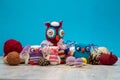 Handmade multi-colored knitted toy owls, skeins with thread, knitting needles, pins on the table. Needlework and children`s