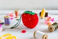 Handmade and needlework. Pin cushion strawberry with a simple ornament and a pair of scissors on a white table. Sewing supplies in