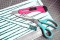 Handmade paper bead templates of green colored floral patterns lying on a cutting mat with pink craft knife and a Royalty Free Stock Photo