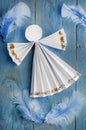 Handmade paper white angel on blue feather background. Royalty Free Stock Photo