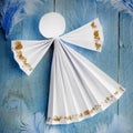 Handmade paper white angel on blue feather background. Royalty Free Stock Photo