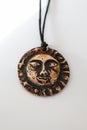Handmade Pendant with Sun Face on Cord, on White. Bronze Charm with Celestial Design Royalty Free Stock Photo