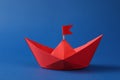 Handmade red paper boat with flag on blue background. Origami art Royalty Free Stock Photo