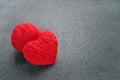 Handmade red yarn ball with heart made of red wool yarn on a gray woolen fabric background. Red warm heart like a symbol of love.