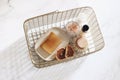 Handmade soap bar, shampoo bottle, dry lemons, wooden brush and Himalayan salt in golden basket. White marble table