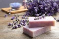 Handmade soap bars with lavender flowers on brown wooden table, closeup