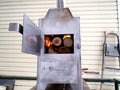 Handmade stainless steel wood stove with open ash pit and oven door, burning firewood inside