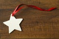 Handmade, star-shaped blank Christmas holiday gift tag with red ribbon decorations on rustic wood background Royalty Free Stock Photo
