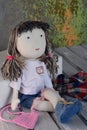 Handmade textile doll with threaded hair on a white wooden background
