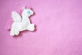 Handmade toy Pegasus on a pink felt background. Handmade pink flat lay. Sewing funny felt pony with wings. Postcard.