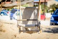 Handmade Wooden Toddler Swing Hanging From Tree over Hot Sand in a Beach Bar in Crete Island, Greece, at Summer. Royalty Free Stock Photo