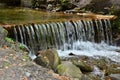 Handmade wooden water drains from small treated beams. A beautiful fragment of a small waterfall