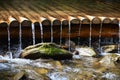 Handmade wooden water drains from small treated beams. A beautiful fragment of a small waterfall