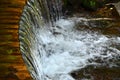 Handmade wooden water drains from small treated beams. A beautiful fragment of a small waterfall