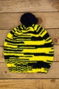 Handmade wool knitted winter yellow and black hat isolated wooden background