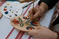 Handpainting on handmade decorative wooden round plate, man`s hand paints a bright floral pattern, Petrykivka painting style Royalty Free Stock Photo