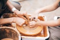 Hands of adult and child making pottery, working with wet clay closeup. Process of making bowl from clay on wheel with dirty hands Royalty Free Stock Photo