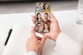 Hands of adult european woman hold phone with headshot of young and millennial people